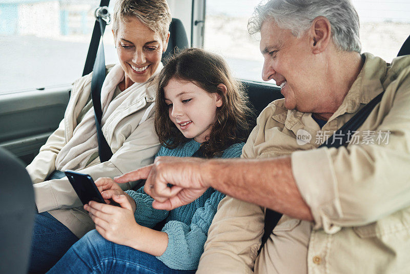 Child, grandparents and phone on road trip in car backseat streaming movie, elearning or helping with education game. 孩子，男人和女人在旅行旅程中非常快乐，并在网上查看目的地